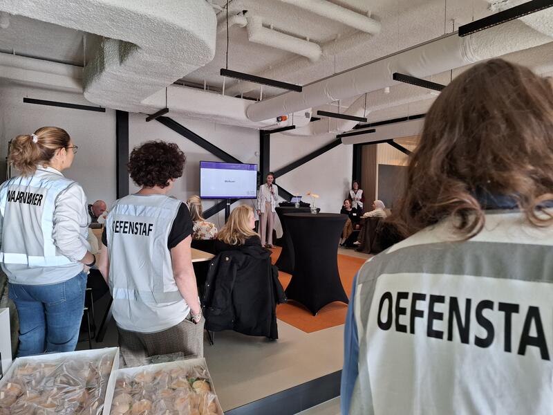 Mensen in grote ruimte bij bijeenkomst, oefenstaf op de rug gekeken