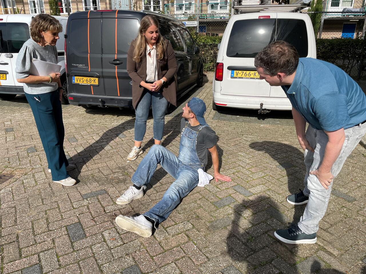 gewonde man op grond drie omstanders