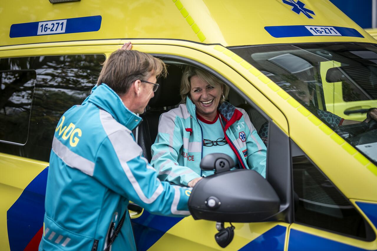 Officier van Dienst Geneeskundig, staand, in gesprek met collega van de RAV Hollands Midden die in ambulance zit