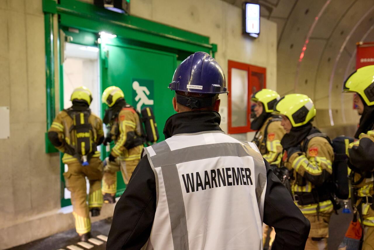 Brandweerlieden in tunnel, waarnemer op rug gezien